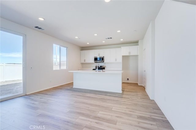 12990 Campbell Ct, Hesperia, CA 92344 - kitchen with visible vents, white cabinets, light countertops, appliances with stainless steel finishes, and light wood-type flooring