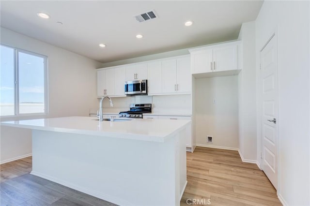 12990 Campbell Ct, Hesperia, CA 92344 - kitchen featuring stainless steel appliances, light wood-style flooring, a sink, and white cabinetry