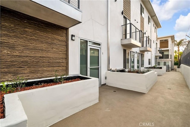 doorway to property featuring a patio, a balcony, and stucco siding