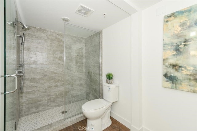 bathroom with toilet, a shower stall, visible vents, and wood finished floors