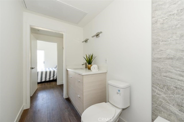 bathroom featuring toilet, baseboards, a sink, and wood finished floors