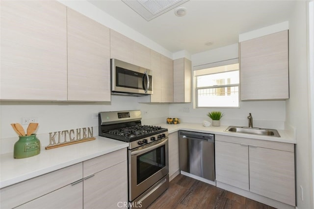 kitchen featuring visible vents, dark wood-type flooring, stainless steel appliances, light countertops, and a sink