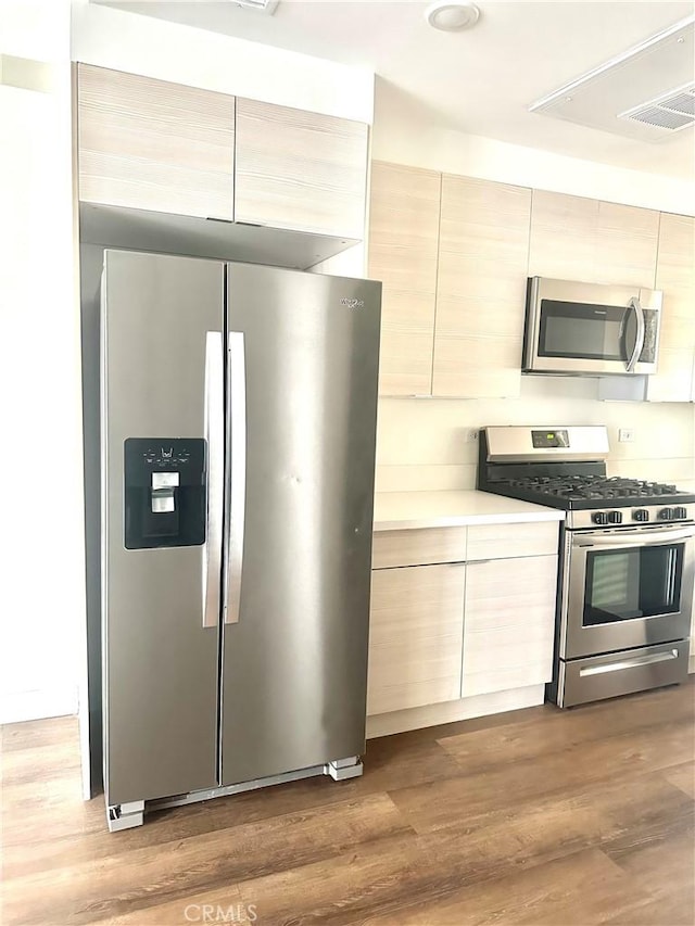 kitchen with stainless steel appliances, wood finished floors, light countertops, visible vents, and modern cabinets