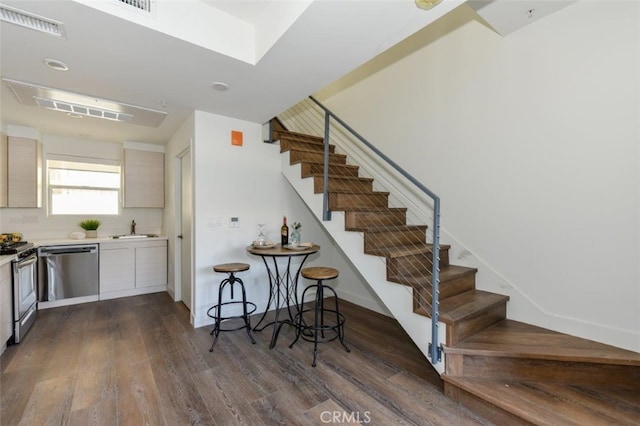 kitchen with dark wood-style flooring, light countertops, appliances with stainless steel finishes, a sink, and baseboards