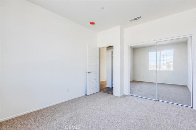 unfurnished bedroom with carpet floors, a closet, visible vents, and baseboards