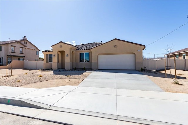 mediterranean / spanish-style house with a tiled roof, concrete driveway, fence, and stucco siding