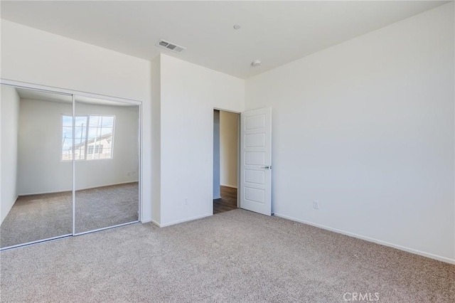 unfurnished bedroom featuring a closet, visible vents, baseboards, and carpet flooring