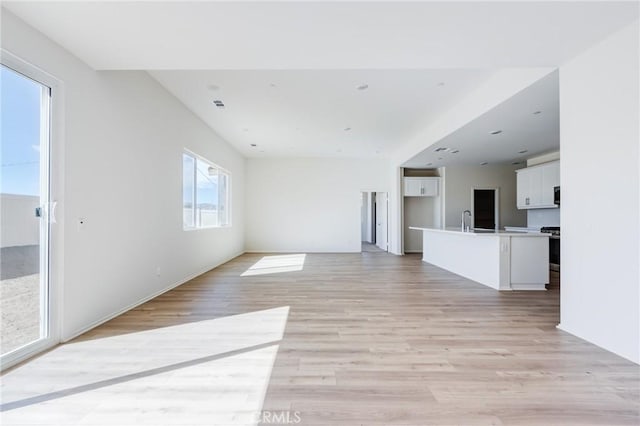 unfurnished living room with a sink and light wood-style flooring