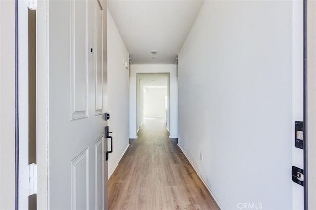 corridor with light wood-type flooring and baseboards