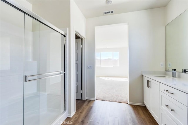 full bathroom with wood finished floors, vanity, visible vents, baseboards, and a stall shower