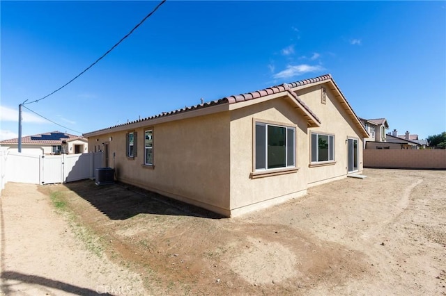 view of side of home featuring fence, a gate, and stucco siding