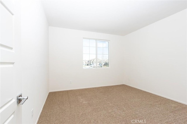 carpeted empty room featuring baseboards