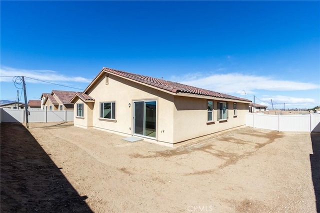 back of property with a fenced backyard, a tiled roof, and stucco siding