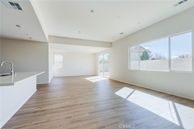 spare room featuring light wood finished floors, visible vents, and a sink