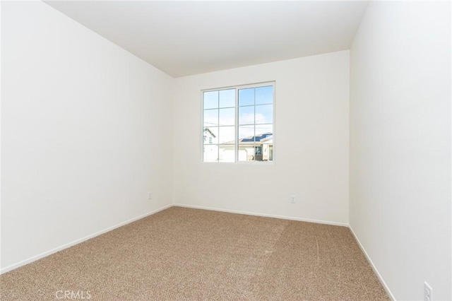 carpeted spare room featuring baseboards