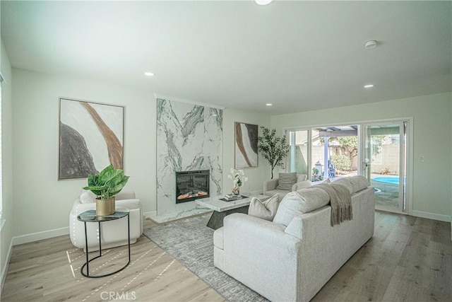 living area featuring recessed lighting, a fireplace, baseboards, and wood finished floors