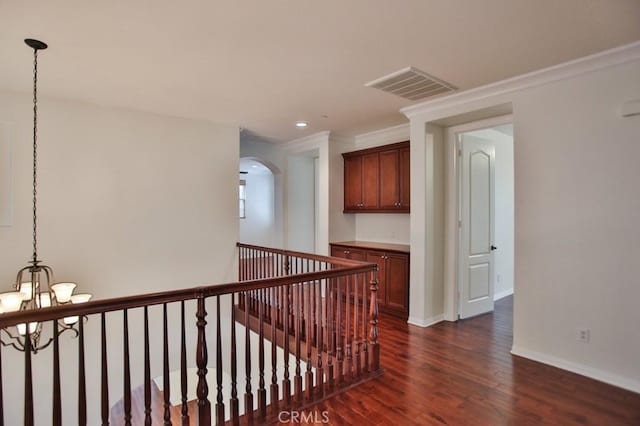 hall with baseboards, visible vents, arched walkways, dark wood-style floors, and a notable chandelier