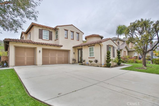 mediterranean / spanish-style home with a front yard, driveway, an attached garage, and stucco siding