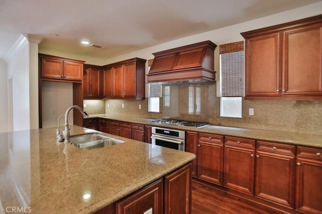 kitchen featuring stainless steel appliances, tasteful backsplash, visible vents, a sink, and premium range hood