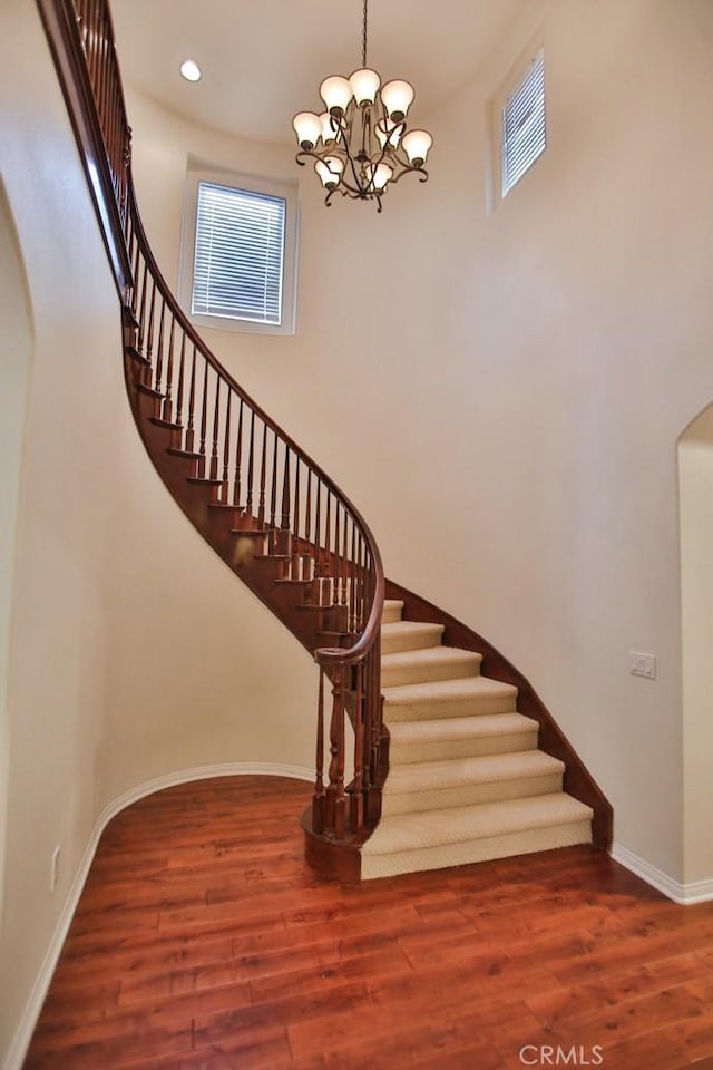 stairway with arched walkways, visible vents, baseboards, and wood finished floors