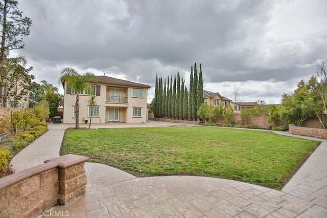 exterior space with a balcony, a patio area, fence, and a front yard