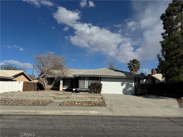 ranch-style home featuring a garage, fence, concrete driveway, and a tiled roof