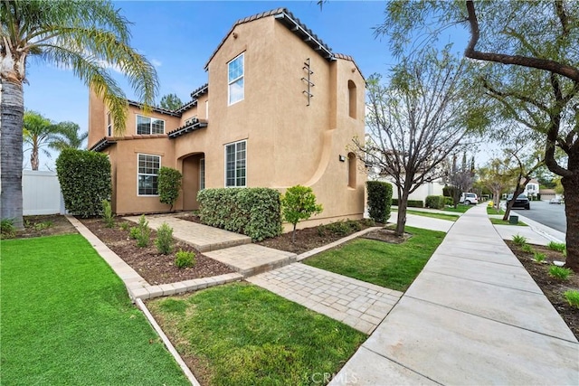 exterior space featuring a tile roof, a front lawn, and stucco siding