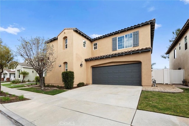 mediterranean / spanish-style house featuring an attached garage, fence, driveway, a tiled roof, and stucco siding