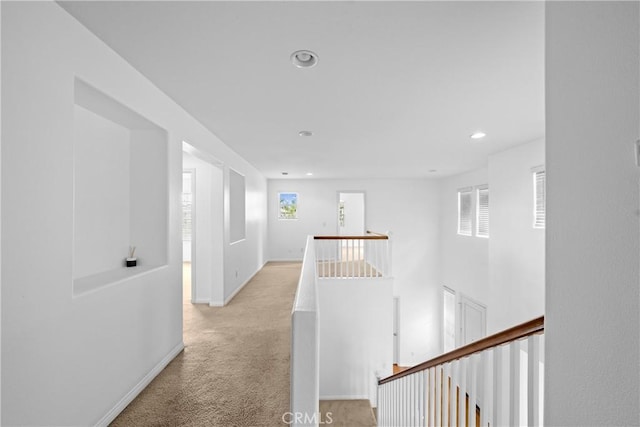 hallway featuring recessed lighting, baseboards, light colored carpet, and an upstairs landing