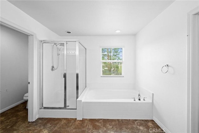 bathroom with toilet, a stall shower, baseboards, and a garden tub