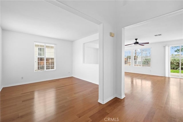 unfurnished room featuring visible vents, baseboards, ceiling fan, and wood finished floors