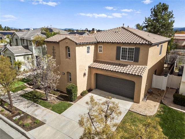 mediterranean / spanish home with a tile roof, fence, driveway, stucco siding, and a chimney