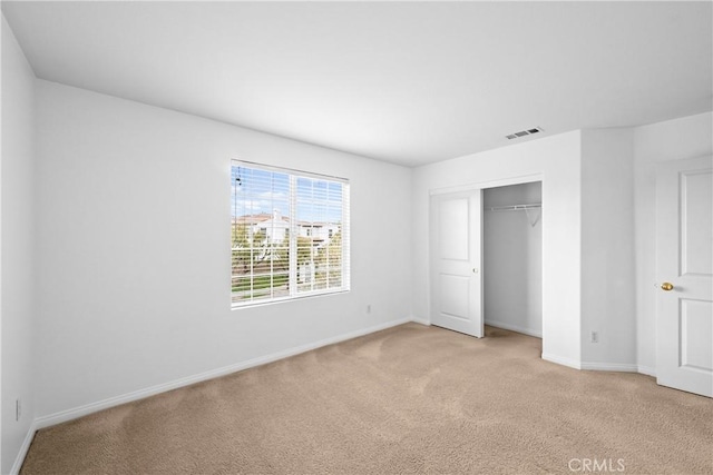 unfurnished bedroom featuring light colored carpet, a closet, visible vents, and baseboards