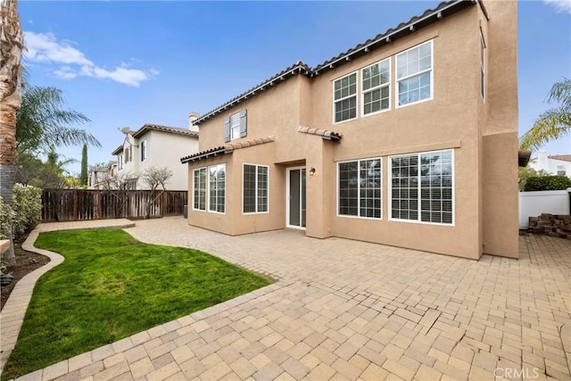 rear view of property with a lawn, a patio area, a fenced backyard, and stucco siding