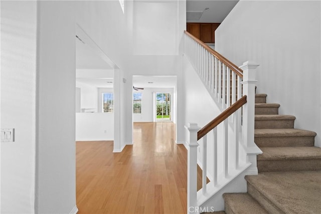 stairway featuring a high ceiling, wood finished floors, and baseboards