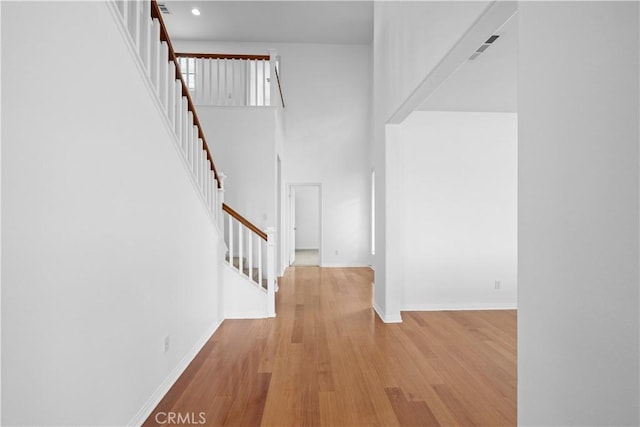 entrance foyer with baseboards, stairway, a towering ceiling, and wood finished floors