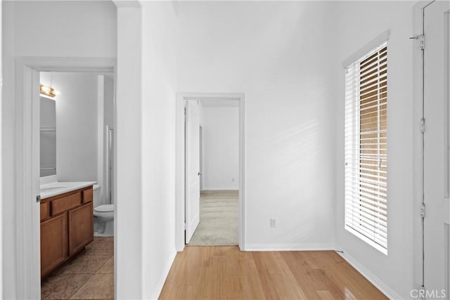 hall with light wood-type flooring and baseboards