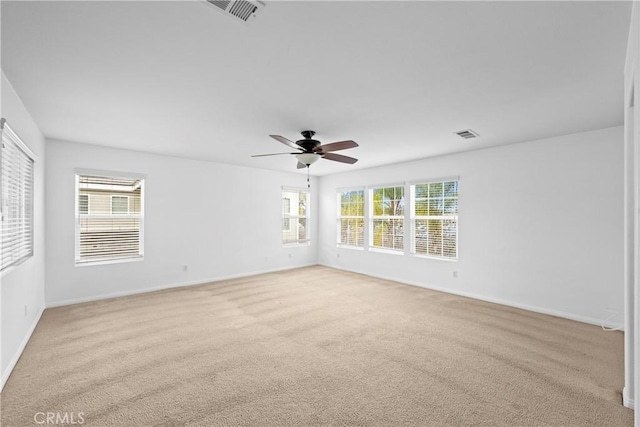 spare room with a ceiling fan, visible vents, light carpet, and baseboards