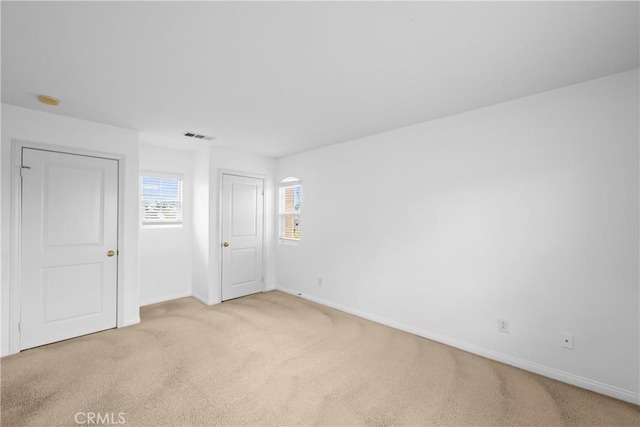 spare room with light carpet, baseboards, and visible vents