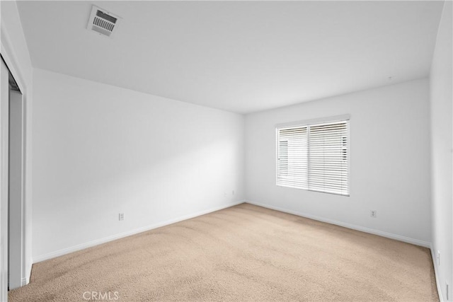 carpeted spare room featuring baseboards and visible vents