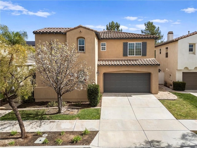 mediterranean / spanish house with concrete driveway, an attached garage, a tile roof, and stucco siding