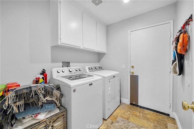 washroom featuring cabinet space, visible vents, baseboards, independent washer and dryer, and stone finish flooring