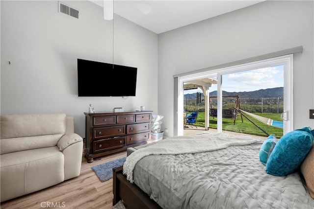 bedroom featuring access to outside, visible vents, and wood finished floors