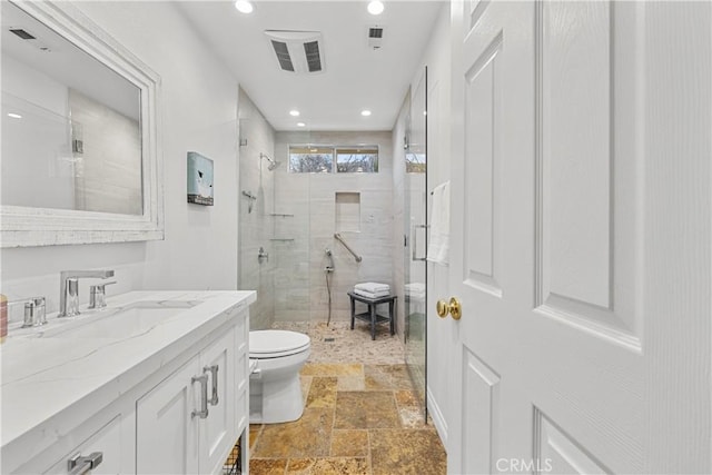 bathroom with toilet, recessed lighting, vanity, a shower stall, and stone tile flooring