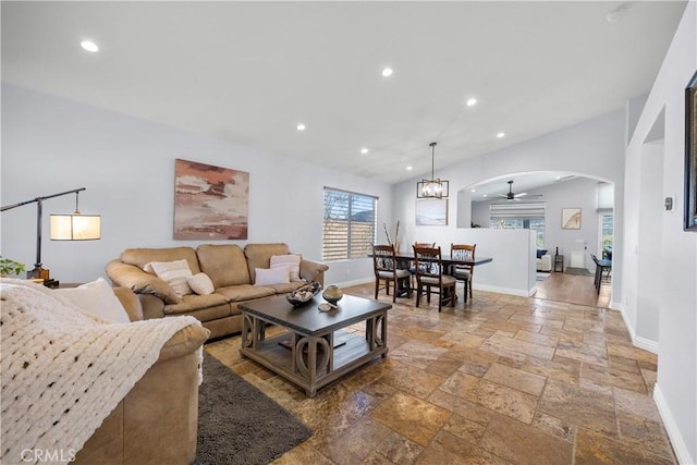 living area featuring arched walkways, plenty of natural light, stone tile flooring, and baseboards