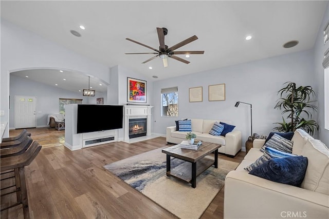 living area featuring lofted ceiling, recessed lighting, wood finished floors, and a glass covered fireplace