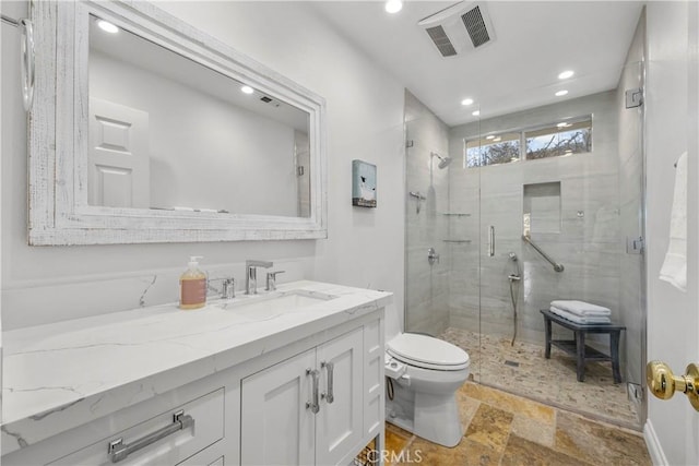 full bathroom with toilet, vanity, visible vents, a stall shower, and stone tile flooring