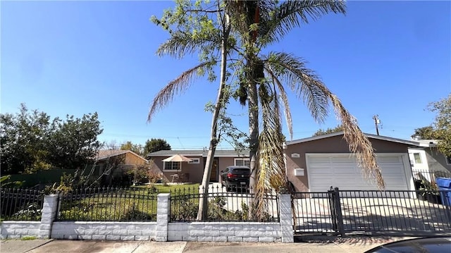 view of front facade with a garage, a fenced front yard, concrete driveway, and stucco siding