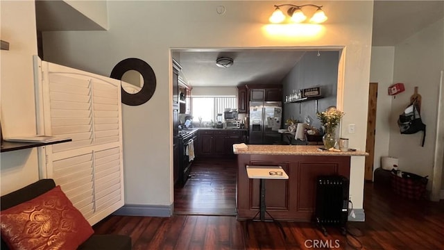 kitchen with stainless steel appliances, dark wood-type flooring, a peninsula, and a kitchen breakfast bar