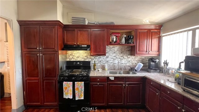 kitchen featuring reddish brown cabinets, under cabinet range hood, vaulted ceiling, black appliances, and a sink